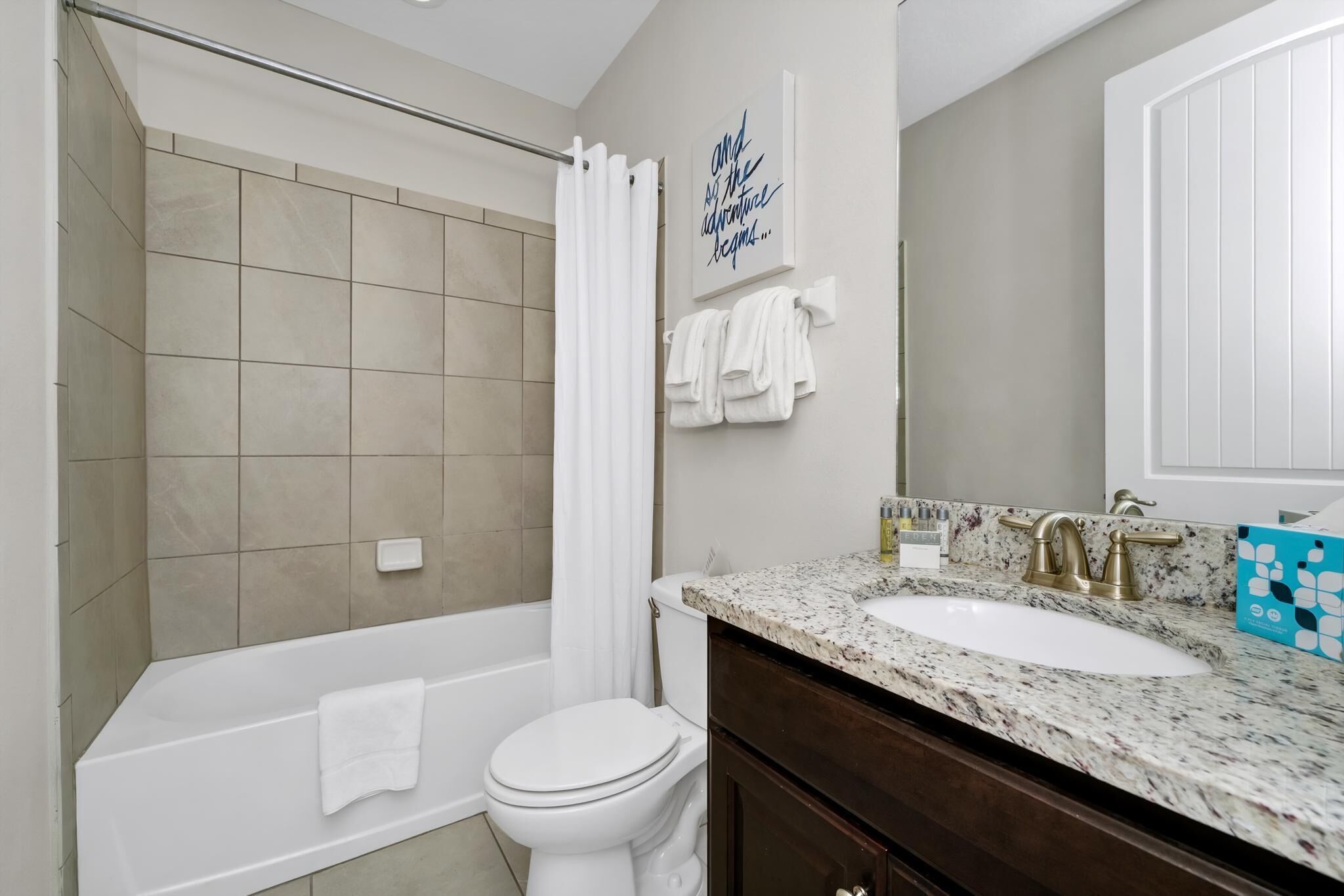 A bathroom with a bathtub, toilet, sink, and a shower curtain.