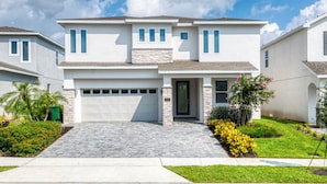 A modern two-story house with a garage, stone accents, and well-maintained landscaping. - Magnificent Home near Disney: Theater, Pool Table & Waterpark - 7448MR (Reunion)
