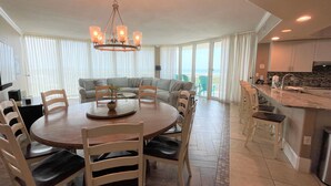 A modern living space with a dining area, a sofa set, and a kitchen.