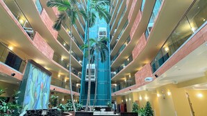 A multi-level atrium with a central staircase, surrounded by seating areas and potted plants.