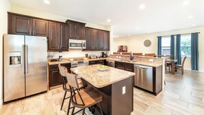 Una cocina moderna con armarios de madera oscura, electrodomésticos de acero inoxidable y una isla grande con taburetes de bar.