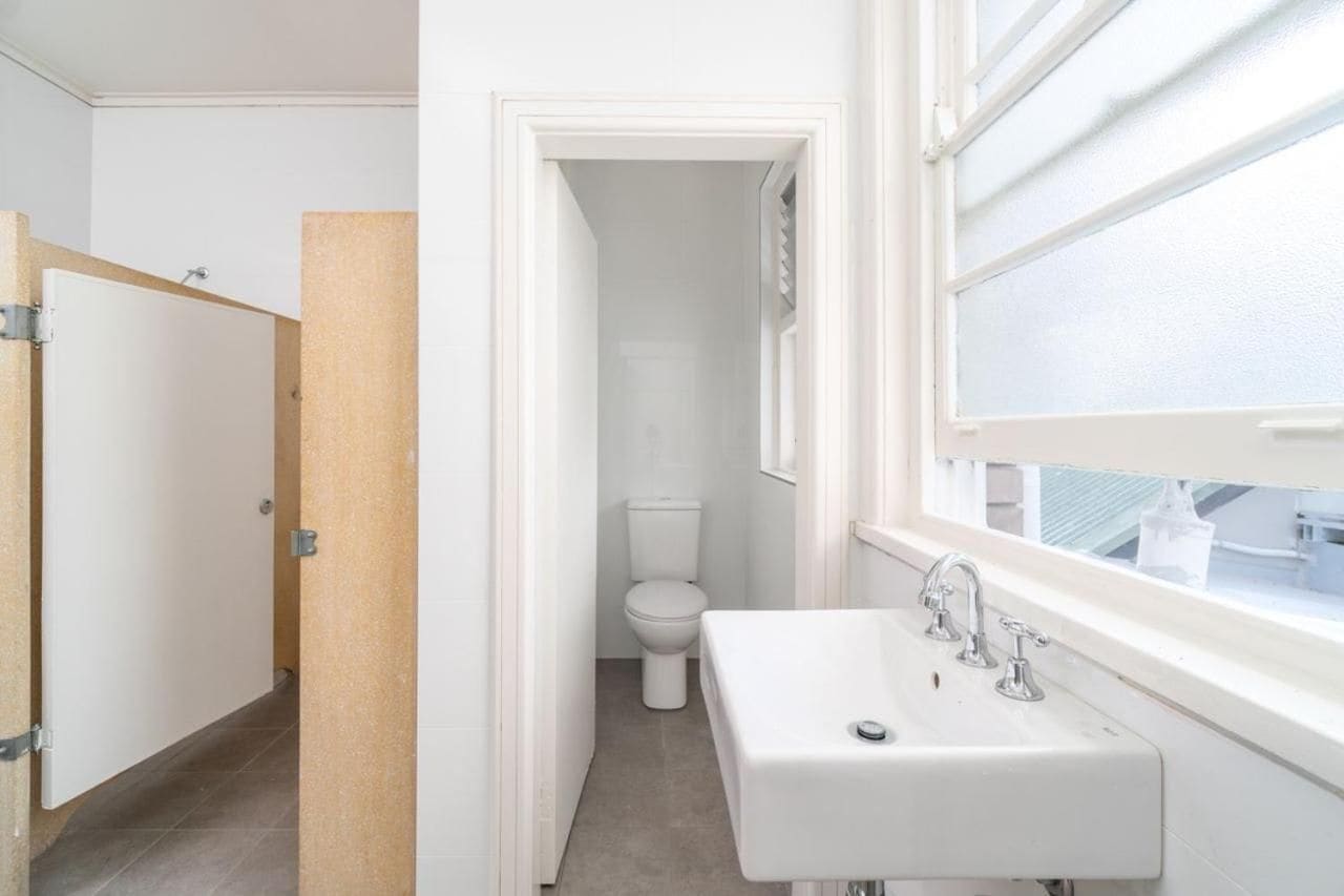 A bathroom with a white sink, a toilet, and a window.