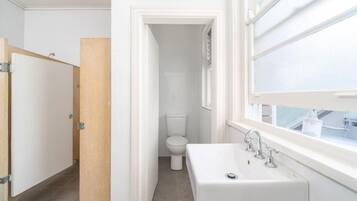 A bathroom with a white sink, a toilet, and a window.