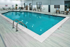 Una piscina interior con señalización clara, incluyendo una advertencia sobre socorrista y prohibido bucear.