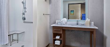 Un baño moderno con ducha, tocador con espejo y perchero.