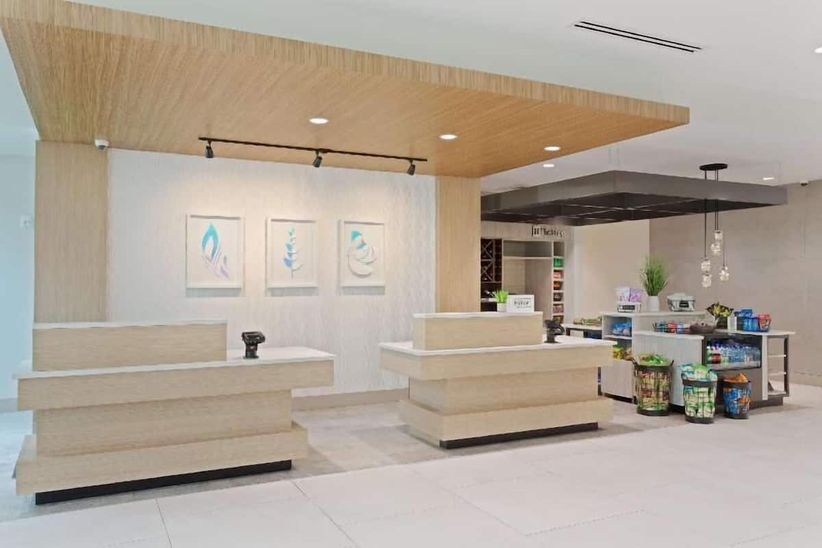 A reception area with a wooden reception desk, a waiting area with a bench, and a counter with various items and a plant.