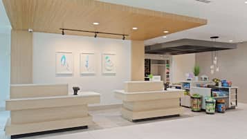 A hotel reception area with a wooden reception desk, a counter with a plant, and a visible 'Hilton' sign.
