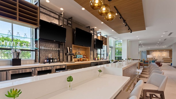 Une cuisine moderne dotée d’un long comptoir, d’appareils électroménagers intégrés et d’une grande fenêtre donnant sur un espace verdoyant.