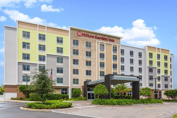 A multi-story Hilton Garden Inn with a central entrance, surrounded by greenery and a parking area. - Hilton Garden Inn Homestead (Homestead)
