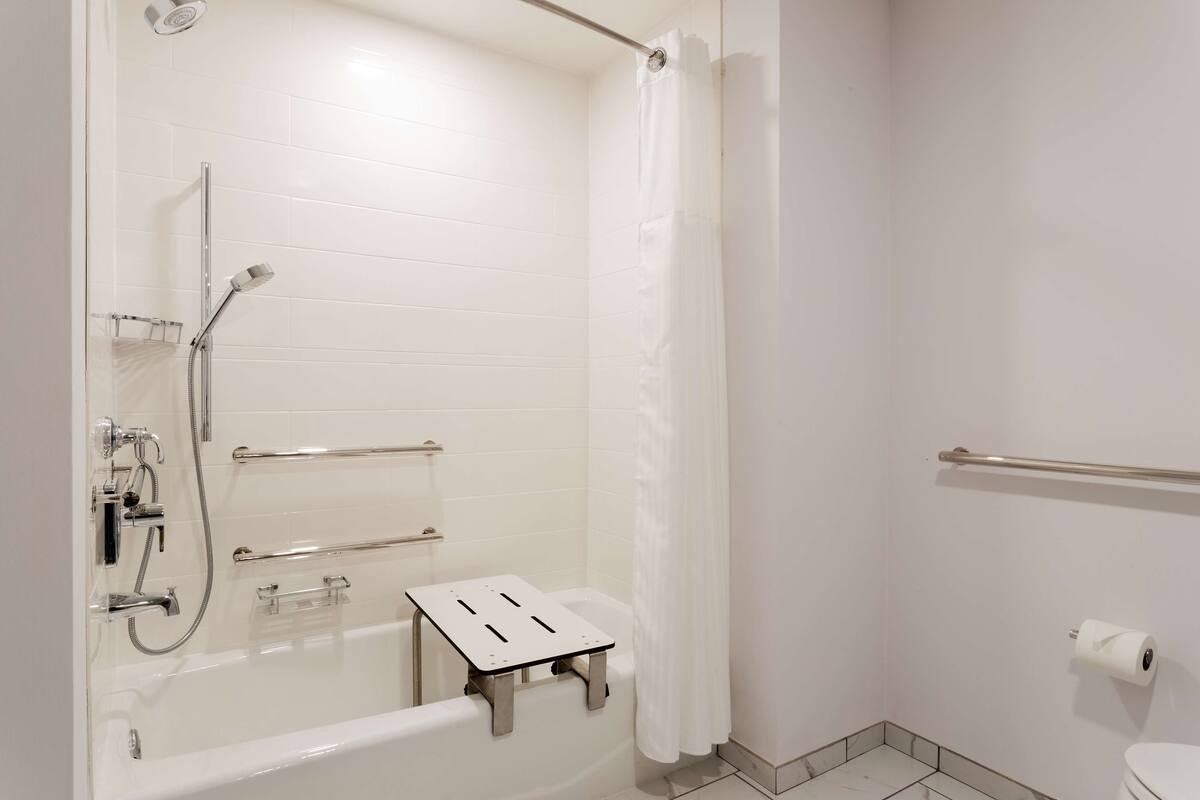 A modern bathroom with a bathtub, shower, and toilet.