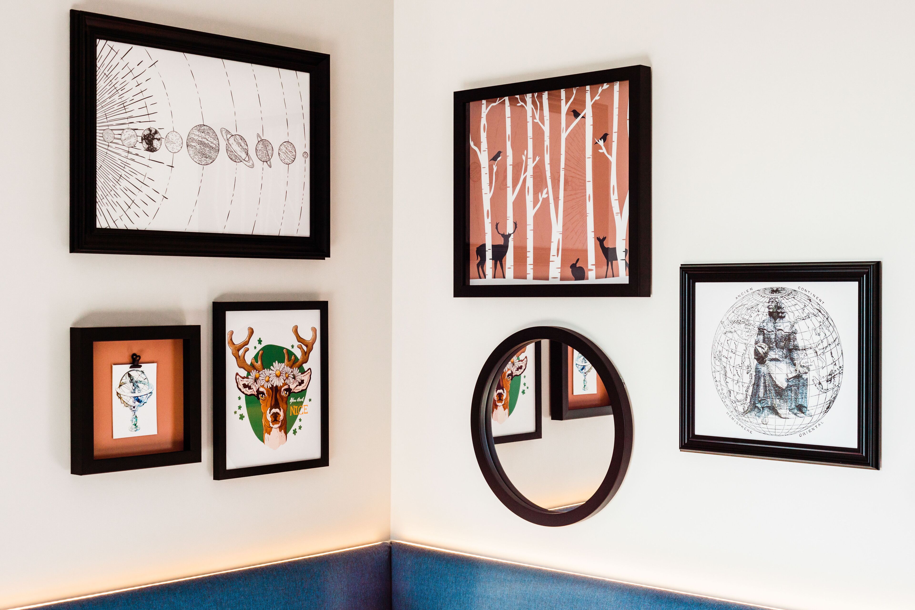 Un mur orné de divers tableaux encadrés, dont un globe terrestre et une illustration représentant un cerf.
