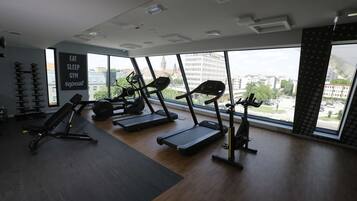Un gimnasio con cintas de correr, una banca y una pared con mensajes motivacionales.