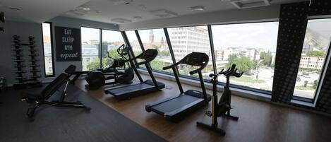 Un gimnasio con cintas de correr, una banca y una pared con mensajes motivacionales.