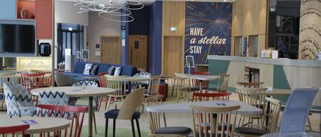 Un restaurant moderne doté de plusieurs espaces de restauration, notamment un bar et des coins salons avec différents types de chaises et de tables.