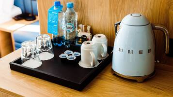 A tray with a coffee maker, glasses, and bottled water on a wooden surface.