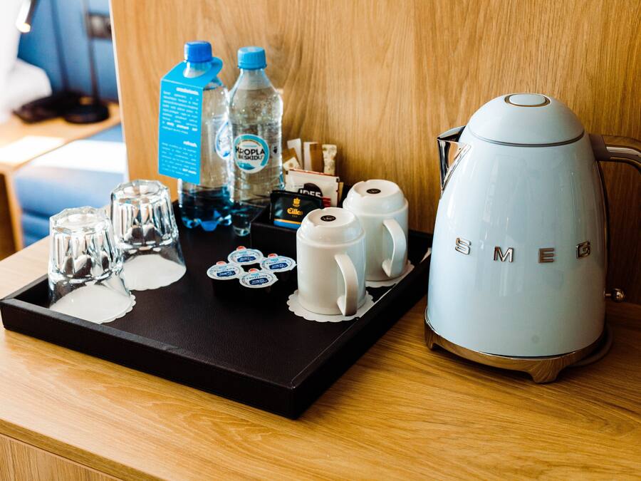 Ein Tablett mit einer Kaffeemaschine, Gläsern und abgefülltem Wasser auf einer Holzoberfläche.