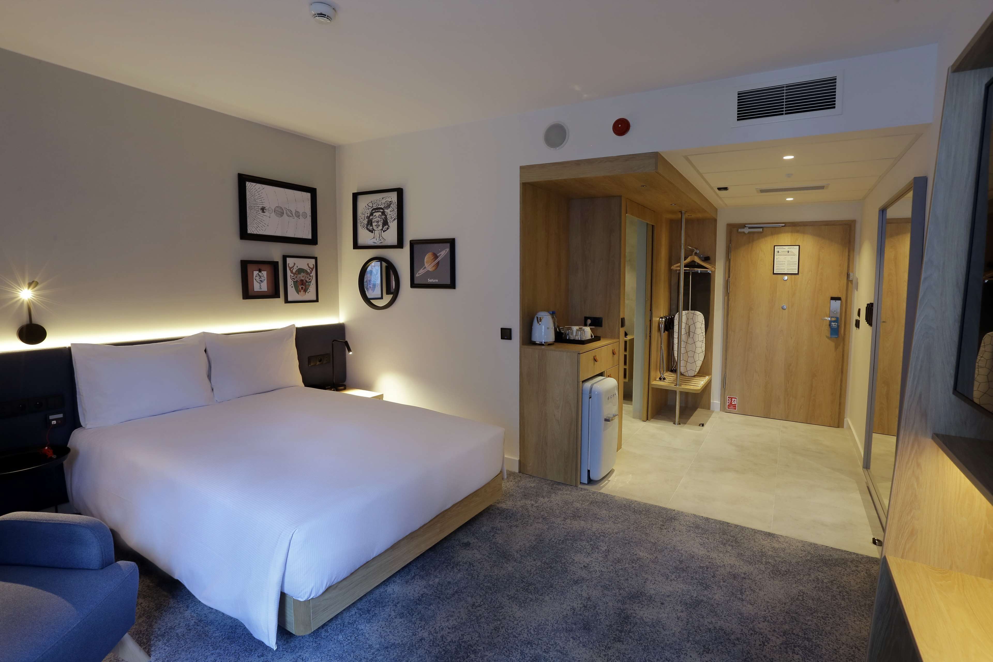 Ett modernt hotellrum med en stor säng, ett skrivbord, en garderob och ett badrum som syns genom en öppen dörr.