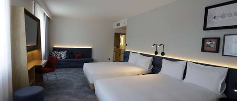 A modern hotel room with two beds, a desk, a chair, and a large window.