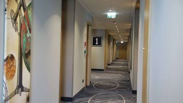 Ein Hotelkorridor mit Teppichboden, einer Nummertafel und einer Tür rechts.
