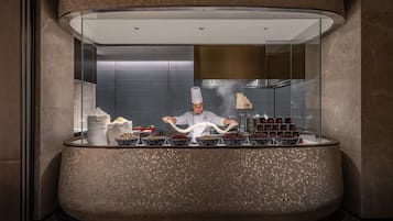 Watch a chef prepare gourmet dishes in a professional kitchen with a sleek, curved ceiling and a clean, minimalist aesthetic.