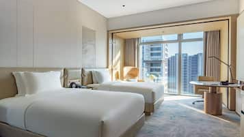 A modern hotel room with a large bed, a desk, and a view of tall buildings.