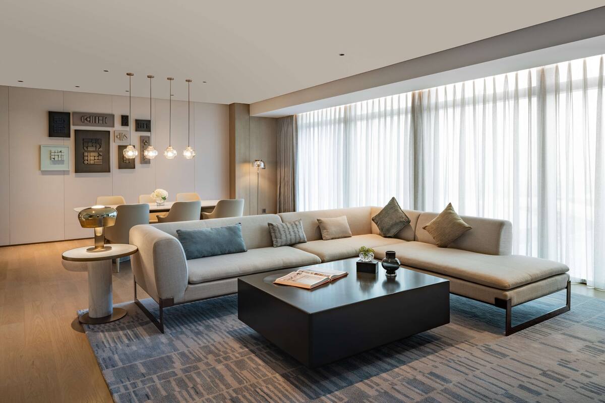 A modern living room with a sectional sofa, a coffee table, and a side table with a lamp.