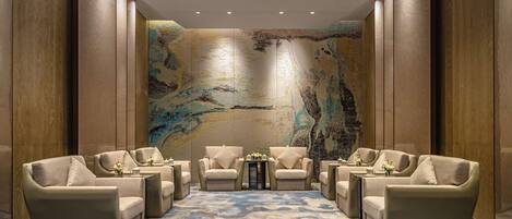 A spacious lounge area with a large abstract mural on the back wall, comfortable seating, and a patterned carpet.