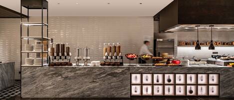 Una cocina moderna con encimeras de mármol, una estación de café y un chef preparando comida.
