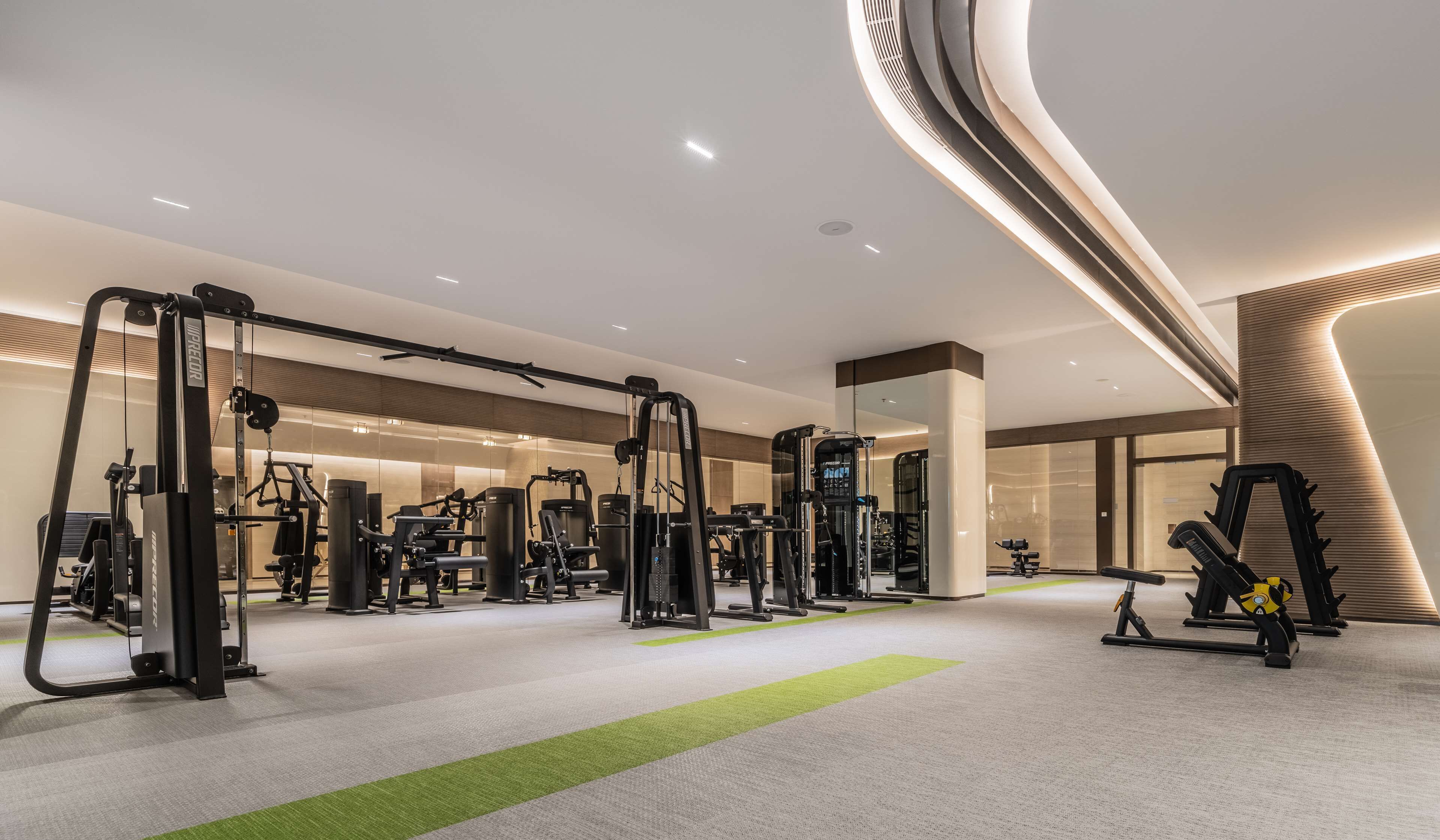 A modern gym with various exercise machines, a green turf area, and a curved wall design.