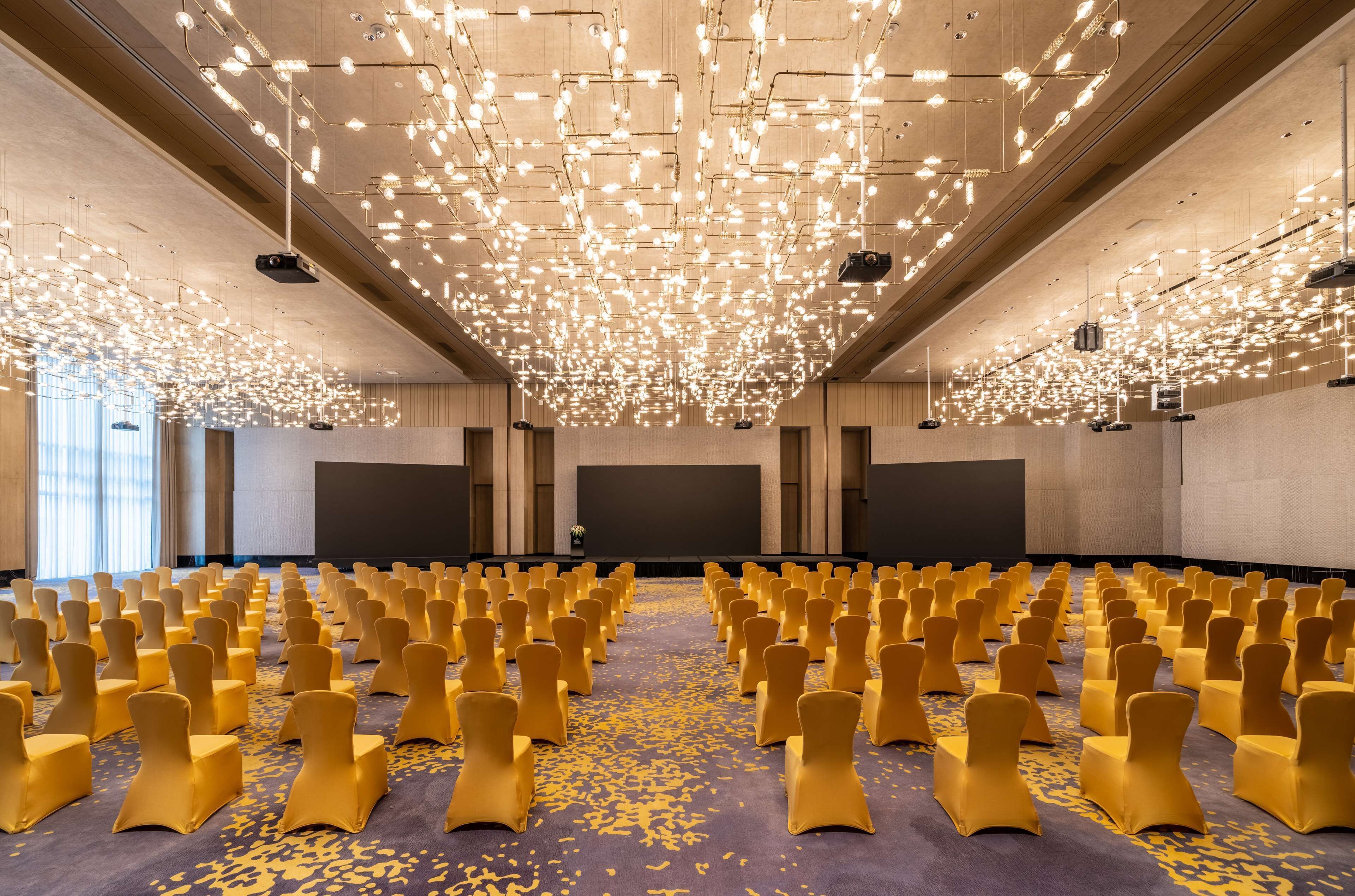 A conference room with rows of chairs and a ceiling filled with lights.