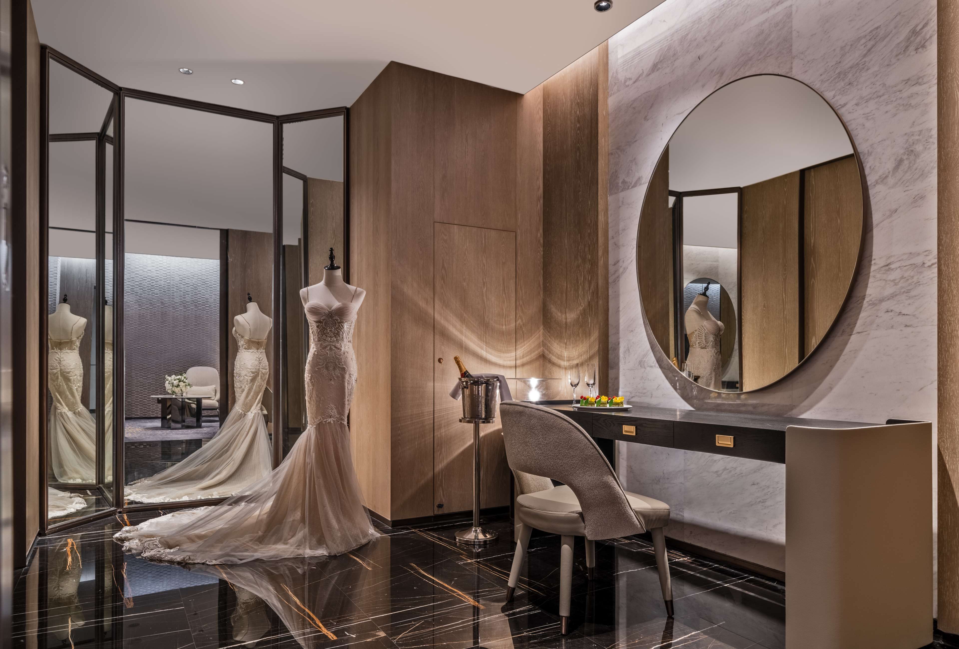 A modern hotel room with a large mirror, a vanity with a marble countertop, and a dress form.