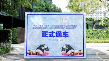 A promotional billboard for a hotel featuring a modern building and a bus.