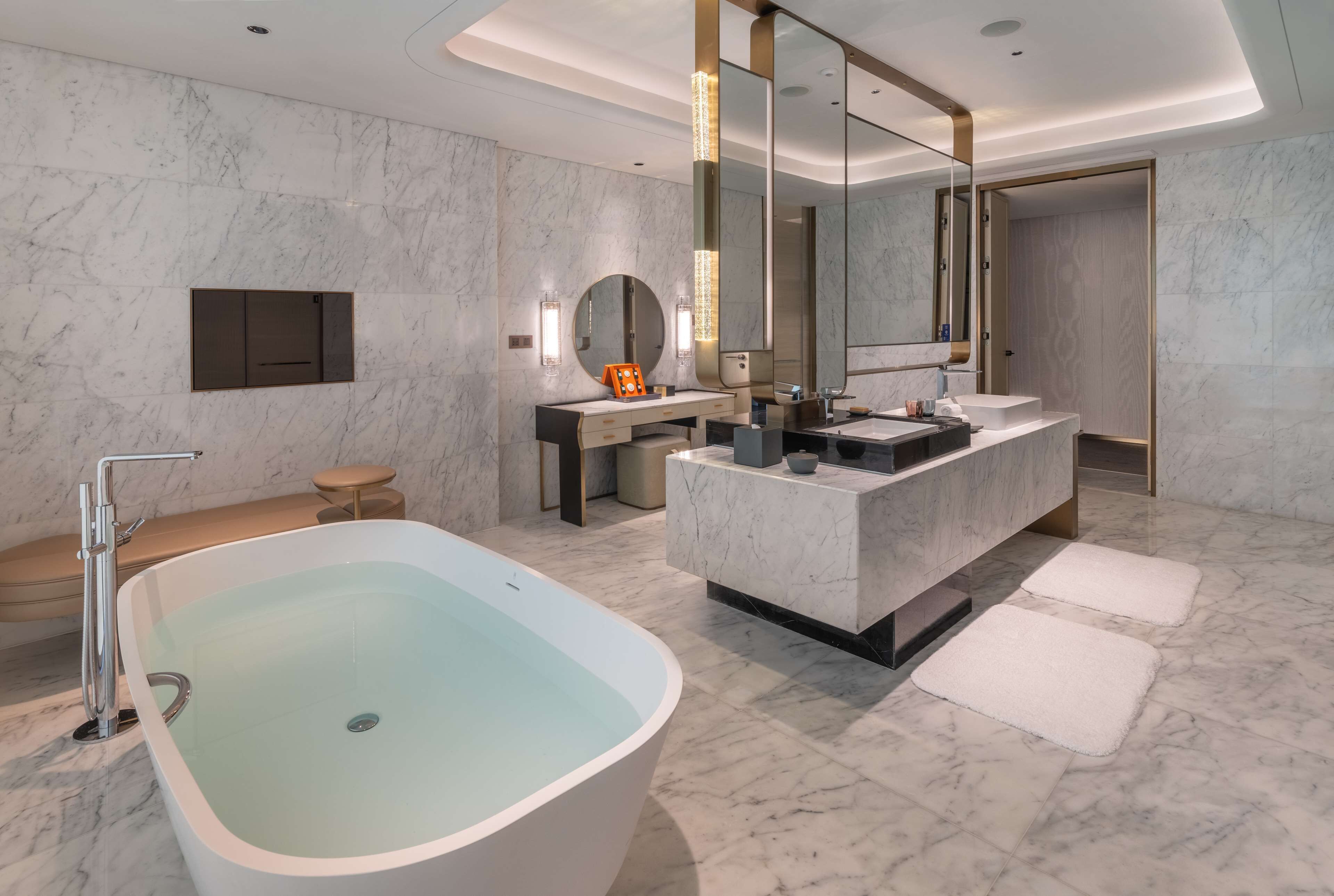 A modern bathroom with a freestanding bathtub, a vanity with a large mirror, and a separate sink area.