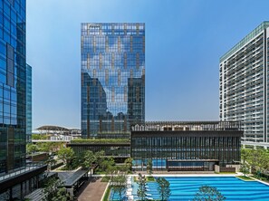 A modern hotel with a glass facade, a rooftop pool, and a landscaped courtyard. - Hilton Shenzhen World Exhibition & Convention Center (Shenzhen)