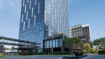 A modern glass building with a prominent logo at the top.