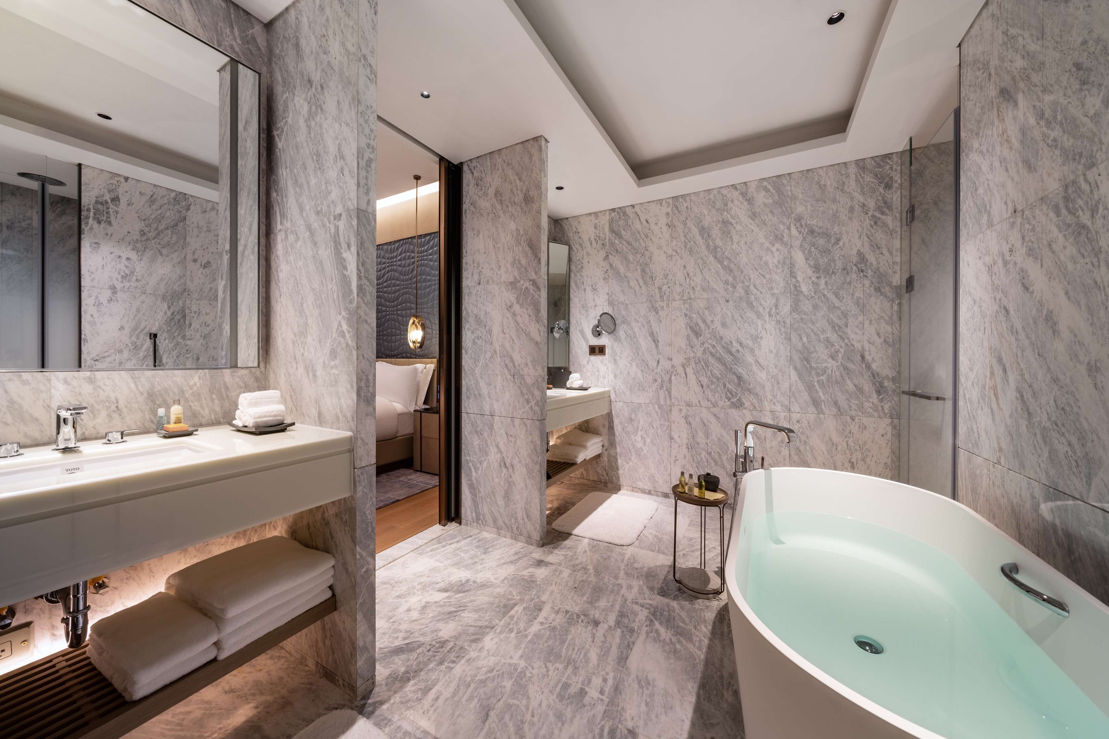A modern bathroom with a large bathtub, a vanity with a mirror, and a shower area.
