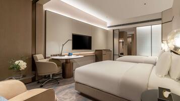 Una habitación de hotel moderna con una cama grande, un escritorio con computadora, una silla, un televisor y una mesita de noche.