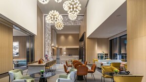 Een ruime lobby met moderne meubels, een bar in het midden en grote ramen die zorgen voor natuurlijk licht.