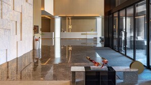 Een moderne lobby met een gestreept plafond, een receptiebalie en een glazen scheidingswand.