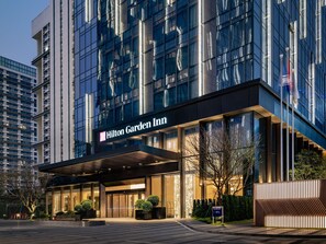 Un moderno hotel Hilton Garden Inn con un ingresso ben visibile, ampie finestre e una facciata luminosa.