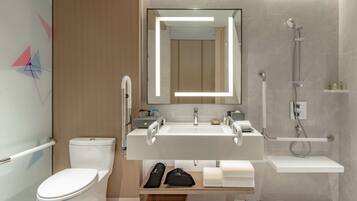 A modern bathroom with a toilet, a sink with a mirror, a shower, and a towel rack.