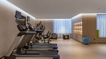 A modern gym with treadmills, stationary bikes, and a rowing machine.