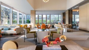 Een ruime, moderne lounge met diverse zitplaatsen, grote ramen met uitzicht op de omgeving, en moderne verlichting.