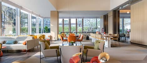 Een ruime, moderne lounge met diverse zitplaatsen, grote ramen met uitzicht op de omgeving, en moderne verlichting.