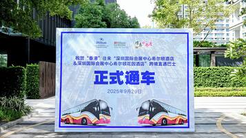 A promotional billboard for a hotel featuring a modern building and a bus.