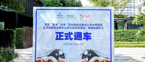 A promotional billboard for a hotel featuring a modern building and a bus.