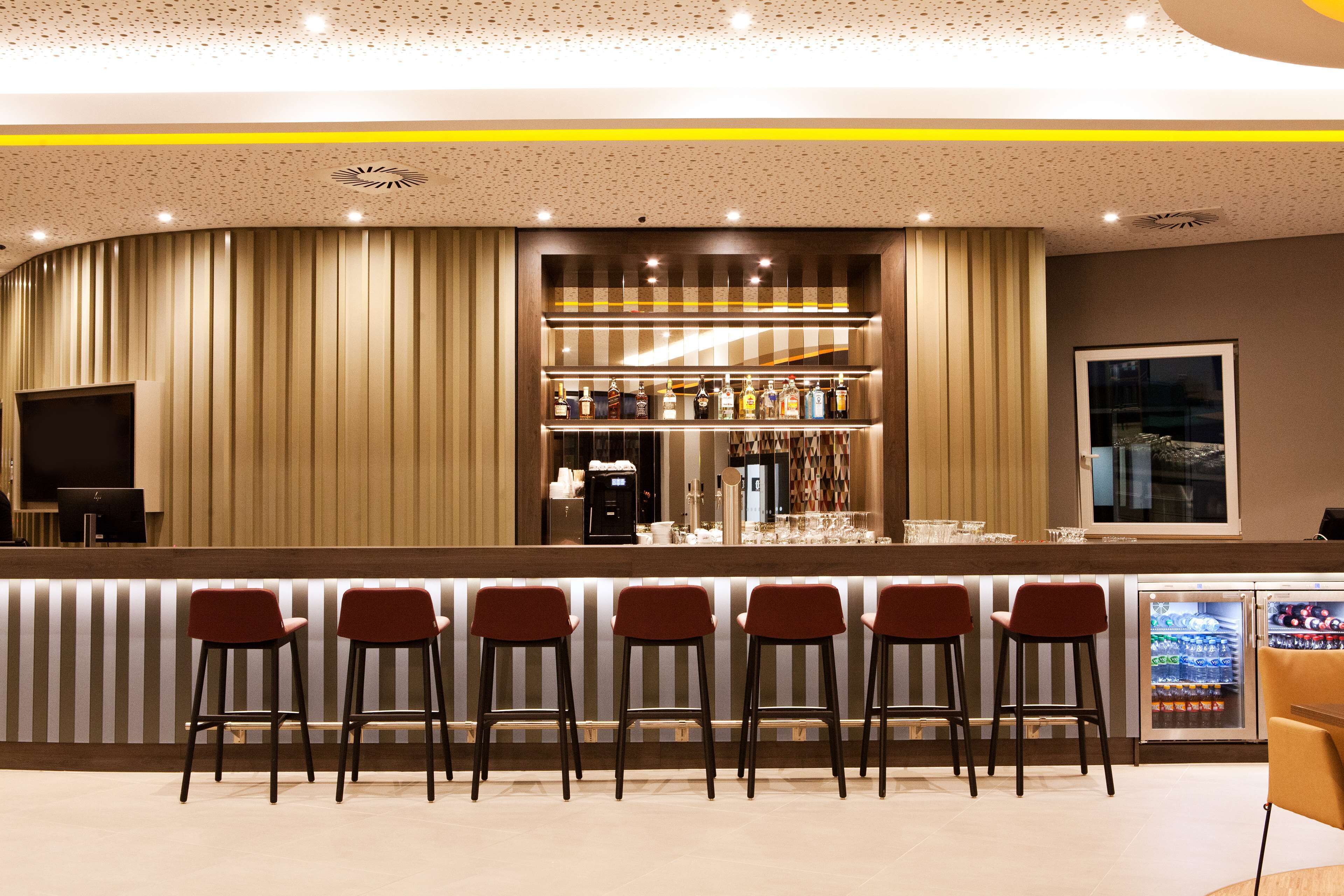 A bar area with a counter, bar stools, a refrigerator, and a television.