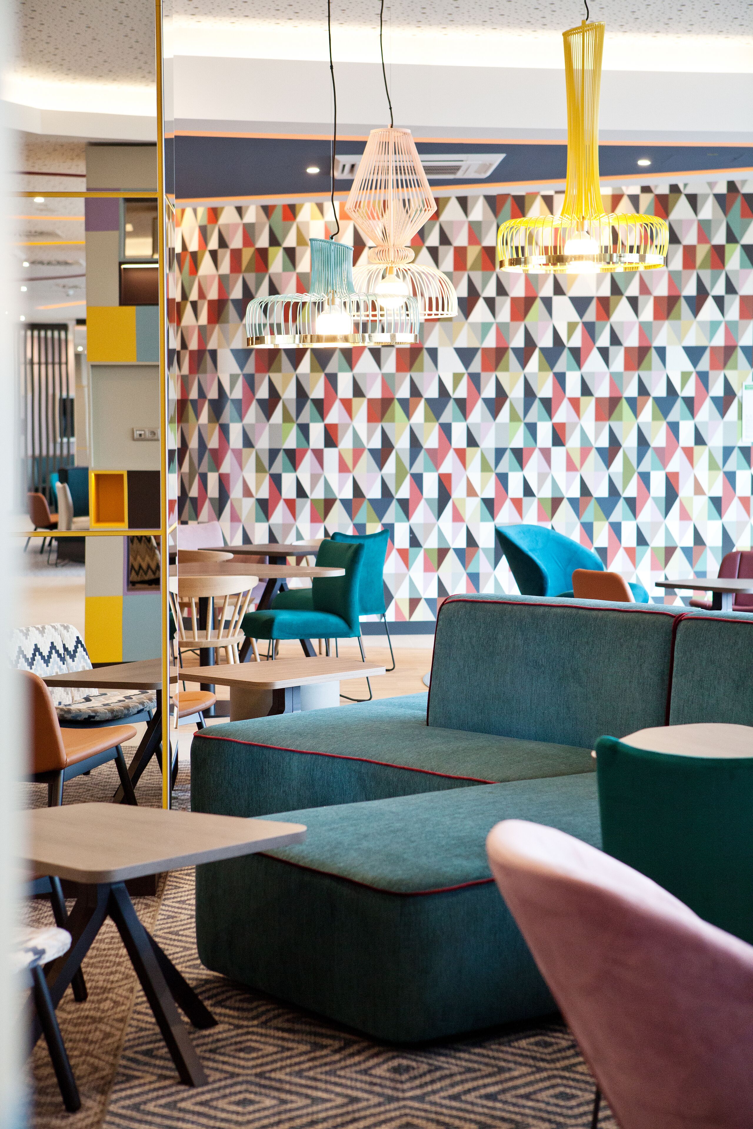 Ett modernt loungeområde med en färgstark, geometrisk vägg, bekväma sittplatser och stilfulla hänglampor.