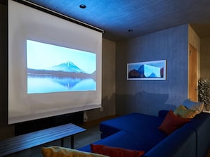 A modern living room with a large flat-screen TV mounted on the wall, a blue sofa, and a small wooden table.