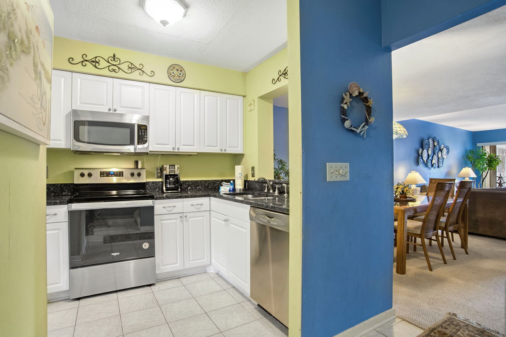 A modern kitchen with white cabinets, stainless steel appliances, and a blue accent wall.